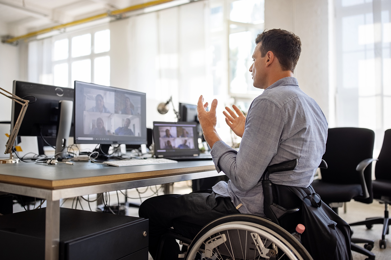 Eine Person in Rollstuhl sitzt vor einem Laptop.